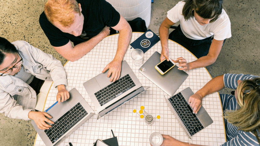 People collaborating on project with papers and laptop
